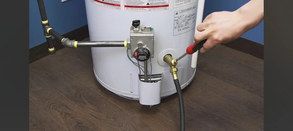 A drain valve being serviced with a bucket below the heater