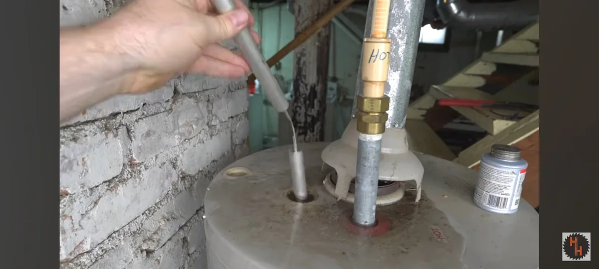 An internal water heater rod being lifted from a storage tank